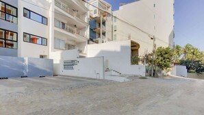 A multi-story residential building with balconies, a gated entrance, and a paved driveway. - Family oasis near the sea - La Cruz Encantada 3A (La Cruz de Huanacaxtle)