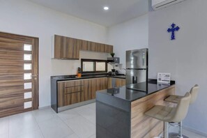 A modern kitchen with a central island, wooden cabinets, and a stainless steel refrigerator. - Family oasis near the sea - La Cruz Encantada 3B (La Cruz de Huanacaxtle)