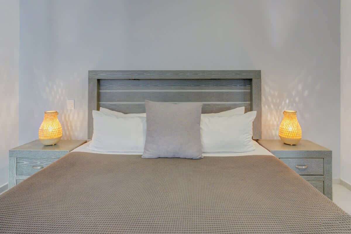 A bed with a textured bedspread, two bedside lamps, and a nightstand with a drawer.