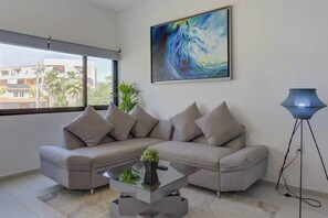 A modern living room with a sectional sofa, a glass coffee table, and a floor lamp. - Family oasis near the sea - La Cruz Encantada 3B (La Cruz de Huanacaxtle)