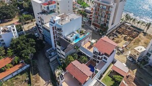 A coastal residential area with modern buildings, a visible swimming pool, and a beach in the background. - Family oasis near the sea - La Cruz Encantada 3B (La Cruz de Huanacaxtle)