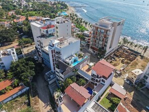 A coastal residential area with modern buildings, a visible swimming pool, and a beach in the background. - Family oasis near the sea - La Cruz Encantada 3B (La Cruz de Huanacaxtle)