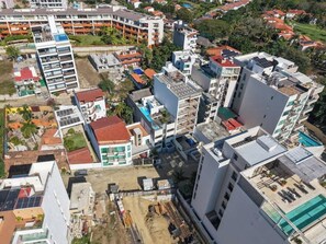 An aerial view of a residential area with various buildings, including a multi-story structure with balconies and a flat-roofed building with solar panels. - Family oasis near the sea - La Cruz Encantada 3B (La Cruz de Huanacaxtle)