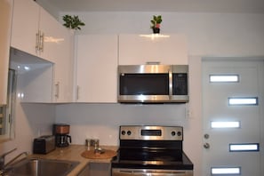 A modern kitchen with stainless steel appliances, including a microwave and oven, and white cabinetry. - Villa Aerio (Carolina)