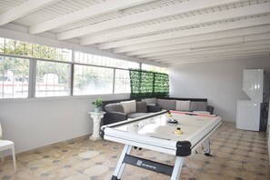 A pool table in a room with a high ceiling, large windows, and a green wall decoration. - Villa Aerio (Carolina)