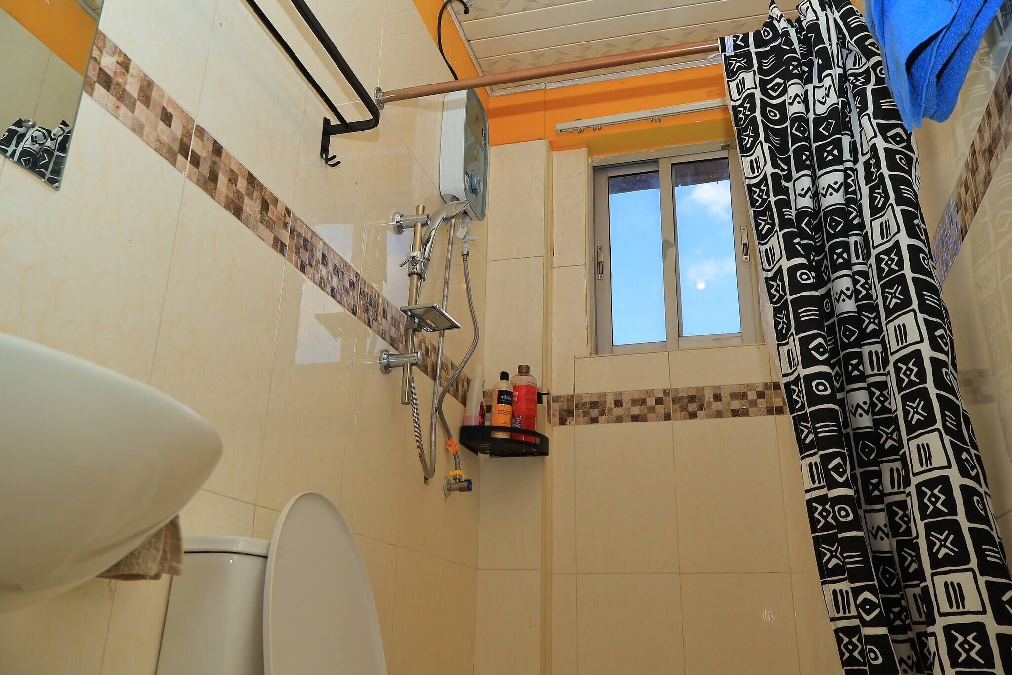 A bathroom with a toilet, shower, and a window.