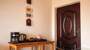 Habitació amb taula de fusta, cafetera i una porta amb un panell decoratiu.