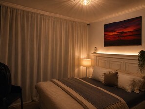 Ein Hotelzimmer mit Bett, Lampe, einem Gemälde und Blick ins Freie.