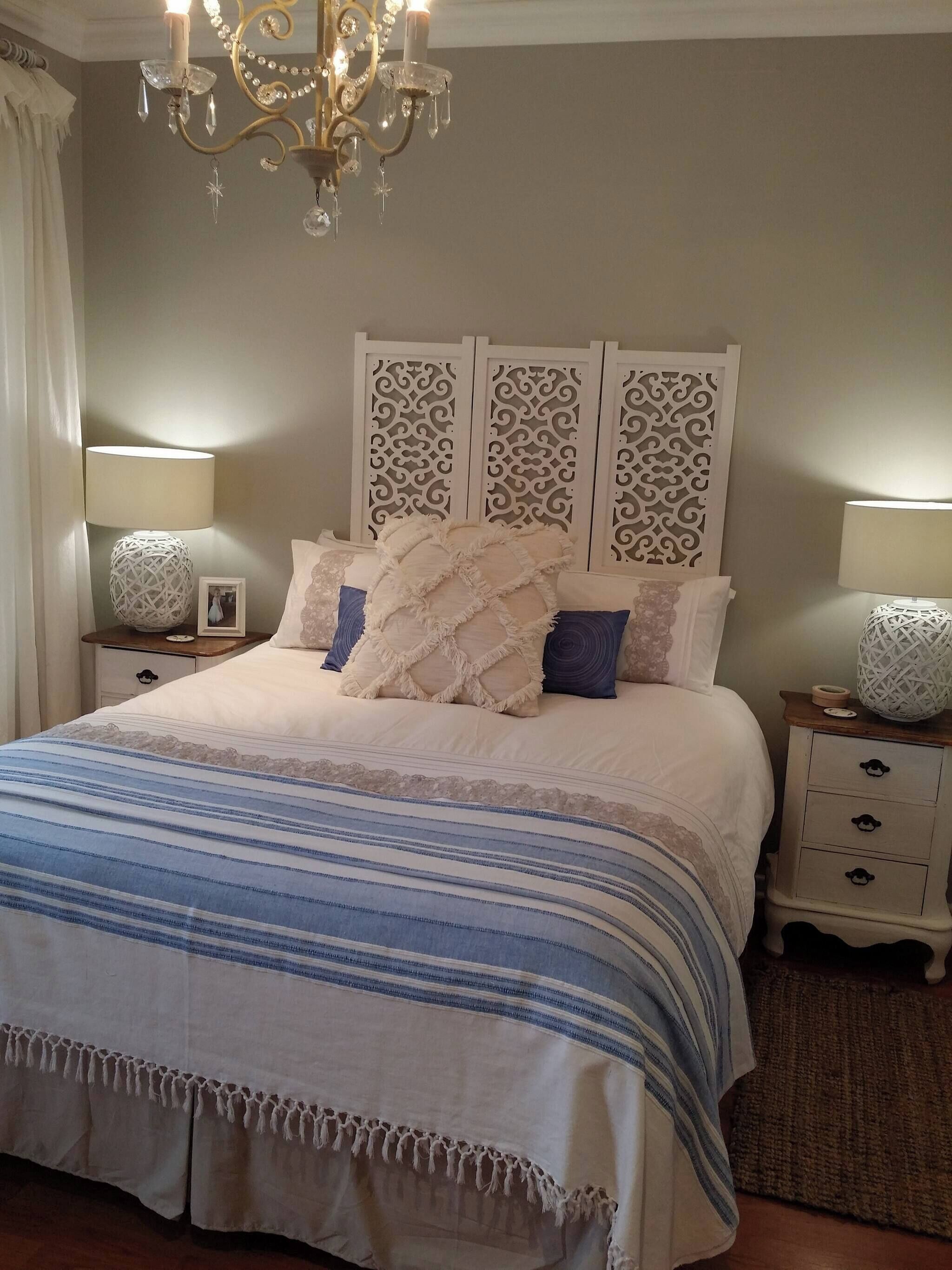 Une chambre à coucher comprenant un lit, deux tables de chevet, un lustre et des panneaux décoratifs sur les murs.
