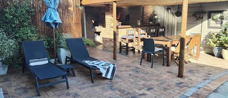 A patio with a pool, lounge chairs, a table, and a pergola.