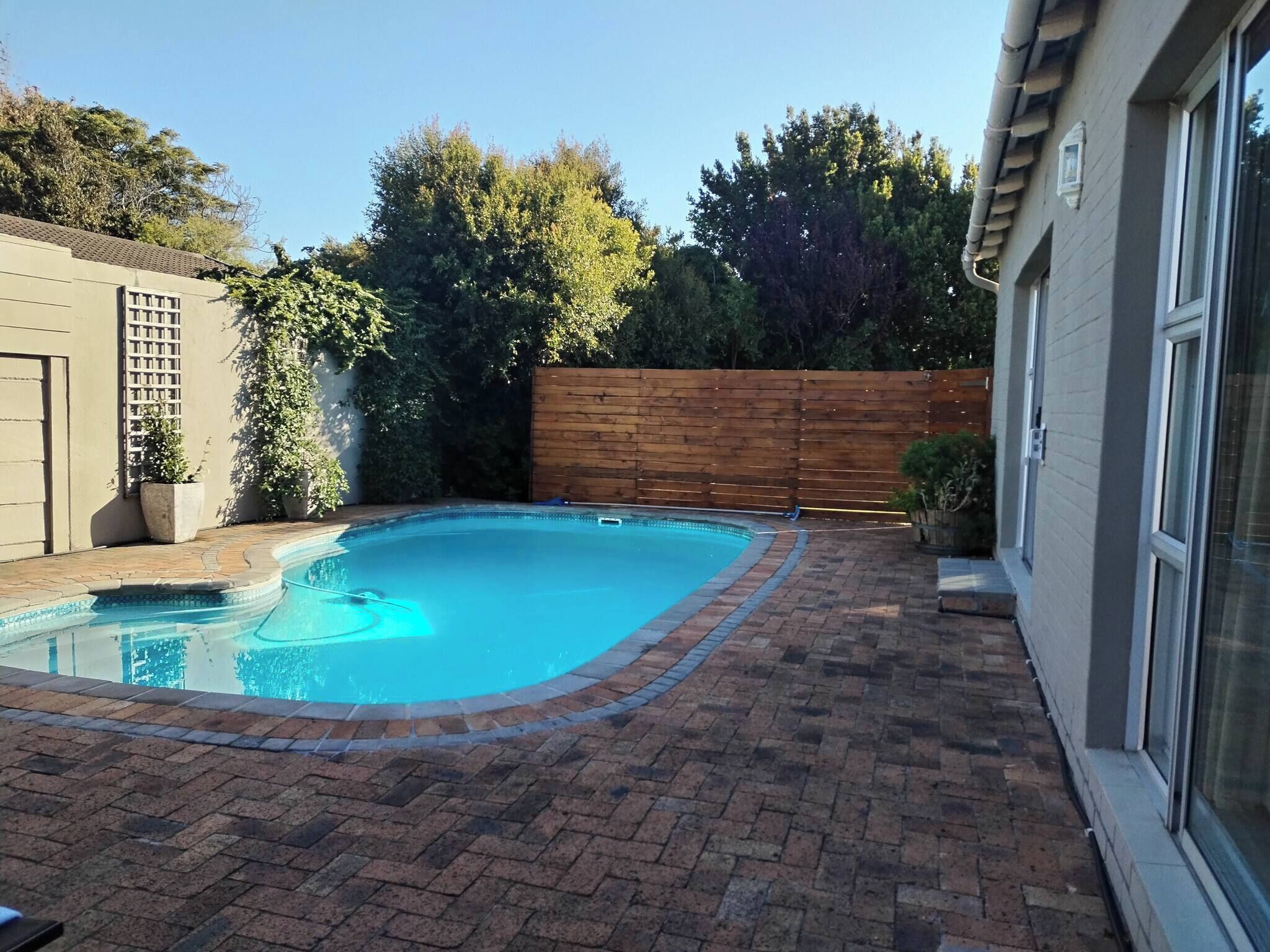 Une piscine rectangulaire entourée d’une terrasse en briques.