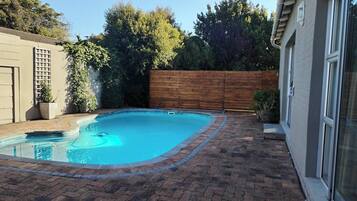 Une piscine rectangulaire entourée d’une terrasse en briques.