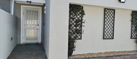 Un bâtiment à l’extérieur blanc, portant le numéro « 41 », doté d’une entrée fermée par un portail et d’un petit jardin agrémenté d’une fenêtre à treillis.