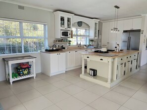 Una cocina moderna con armarios blancos, una isla central y un ventanal con persianas.