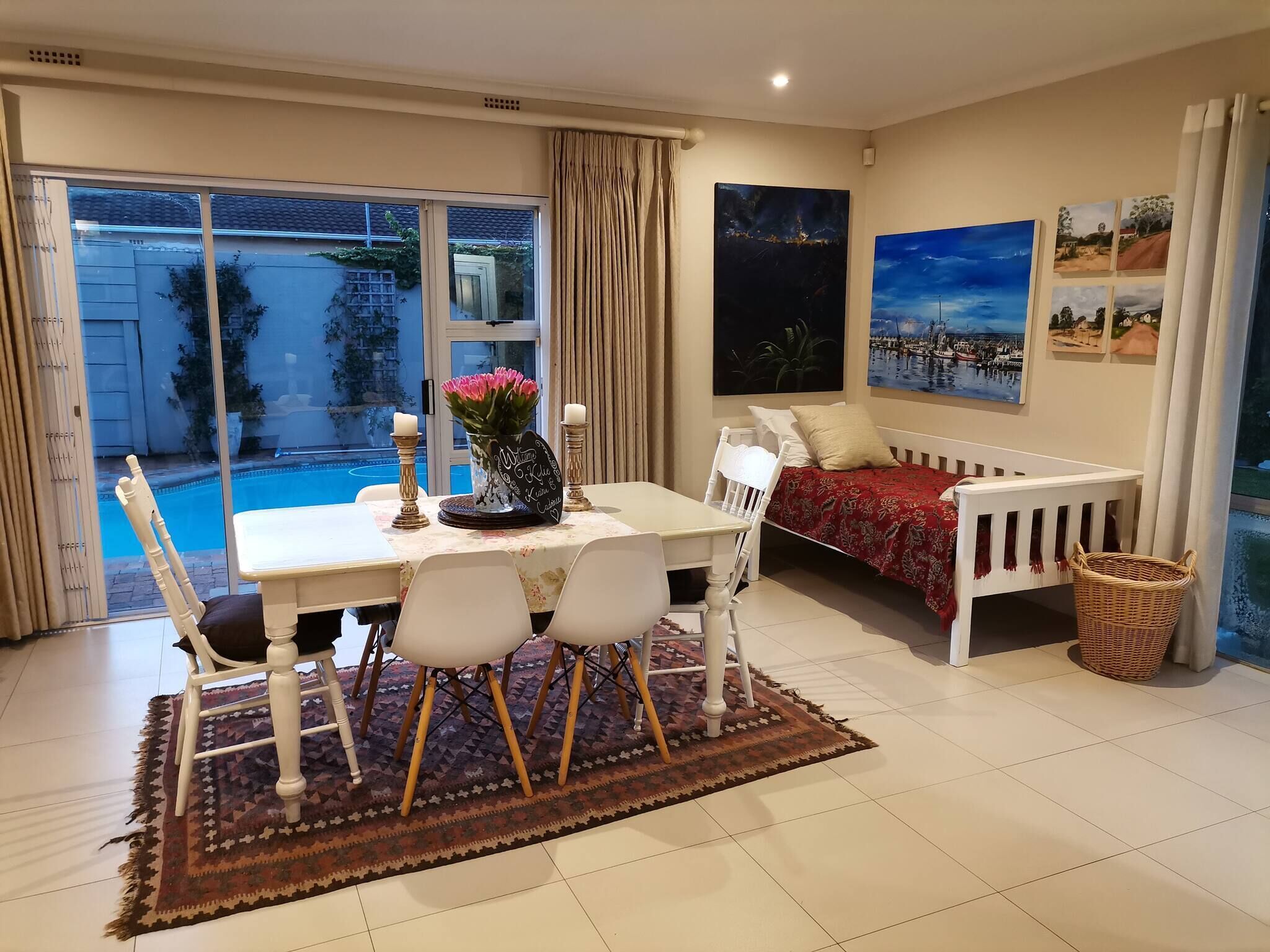A living room with a dining area, a sofa, and a view of a swimming pool.