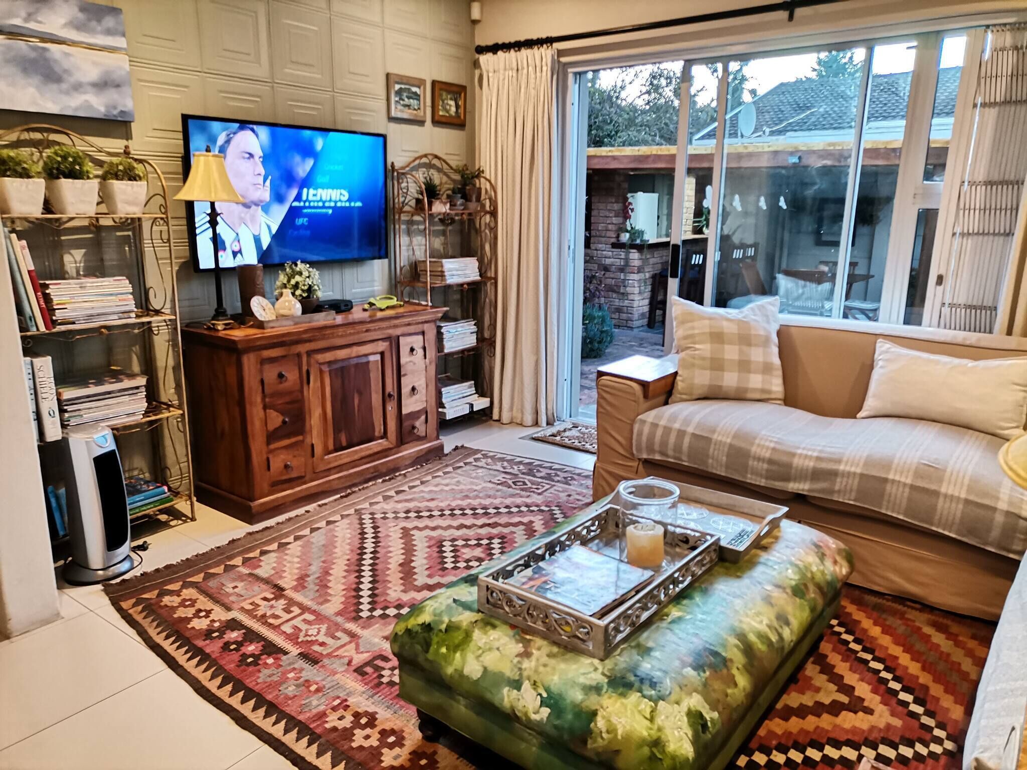 A living room with a television, bookshelves, a sofa, and a patterned rug.