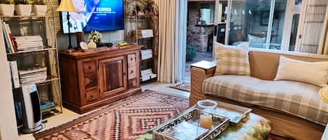 A living room with a television, bookshelves, a sofa, and a patterned rug.