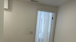 Ein Schlafzimmer mit einem Bett, einer Tür mit durchsichtigem Vorhang und einem Lichtschalter an der Wand.
