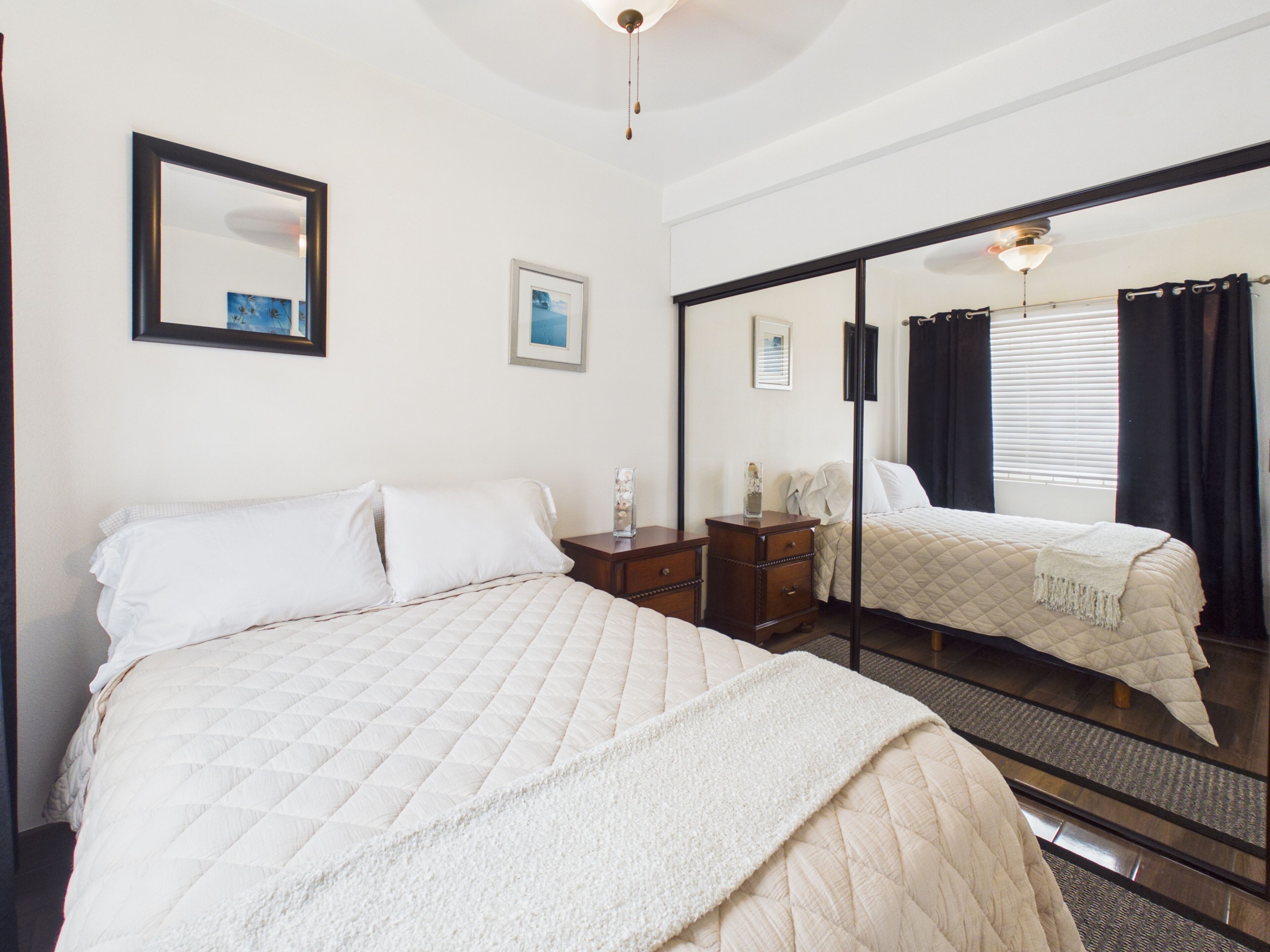 Une chambre d’hôtel avec un grand lit, une commode, un miroir et un ventilateur de plafond.