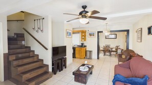 A living room with a sofa, a coffee table, a TV, and a staircase.