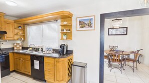 A kitchen with wooden cabinets, a built-in oven, a dishwasher, and a window with blinds.