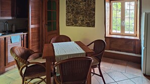 Ein rustikaler Essbereich mit einem Holztisch, Korbstühlen, einer Steinwand und einem Fenster mit Blick.