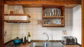 A kitchen with a stainless steel sink, a blue electric stove, a wine bottle, and a toaster.