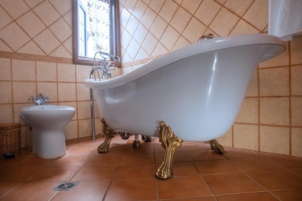 Un baño con una bañera independiente, lavamanos sobre pedestal y un ventanal que proporciona luz natural.