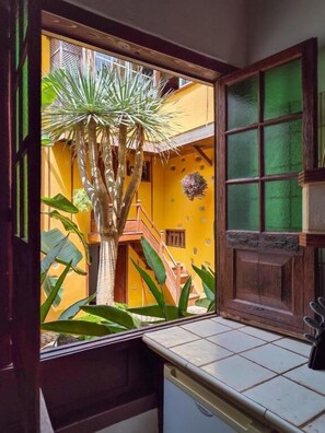 Cocina con ventana que da a un edificio amarillo y una escalera.
