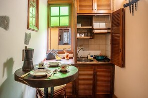 Una cocina compacta con gabinetes de madera, un lavamanos y una mesa de comedor con vajilla.