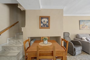 A dining area with a wooden table and chairs, a vase with an owl decoration, and a painting above the table. - 'Duplex by the Sea' Apartment with WiFi and Air Conditioning (Torremolinos)