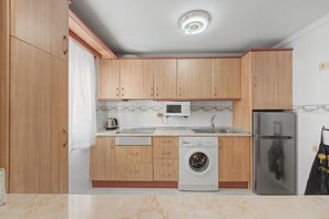 Eine Küche mit Holzausstattung, einer Mikrowelle, einer Waschmaschine und einem Kühlschrank.