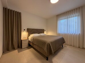 Ein Schlafzimmer mit Bett, Nachttisch und Vorhängen.