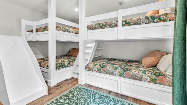 A bunk bed room with a staircase leading to an upper bunk, a patterned bedspread, and a green rug on the floor. - Premier Lake Martin Lakefront Home with Private Boat Ramp, 38 Minutes to Auburn! (Dadeville)