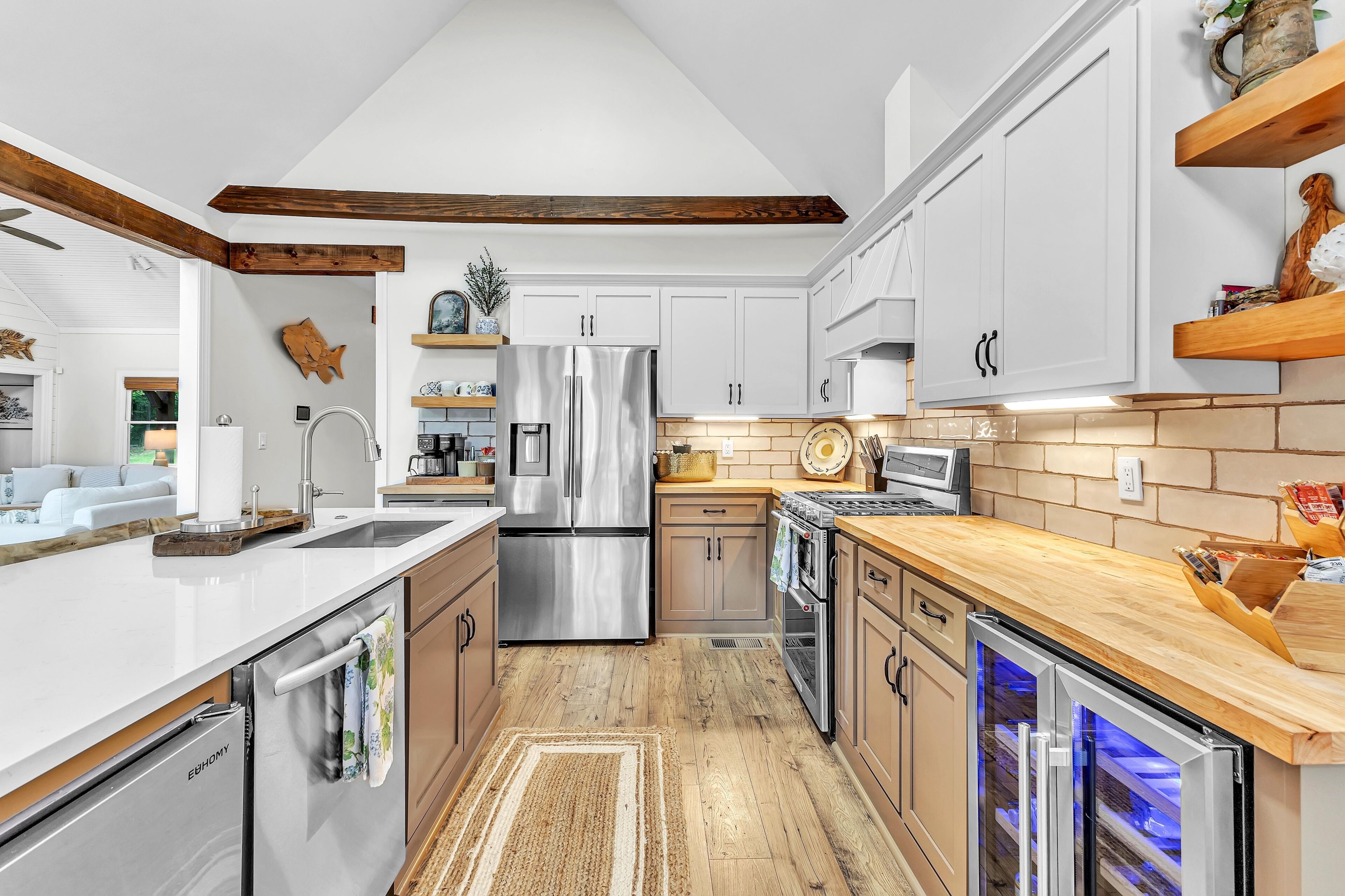 Une cuisine moderne avec des meubles blancs, des appareils électroménagers en acier inoxydable et un plancher en bois.