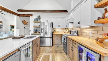 Une cuisine moderne avec des meubles blancs, des appareils électroménagers en acier inoxydable et un plancher en bois.