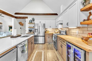 A modern kitchen with white cabinetry, stainless steel appliances, and a wooden floor.