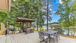 A wooden deck with a table and chairs, a barbecue grill, and a pergola with string lights. - Premier Lake Martin Lakefront Home with Private Boat Ramp, 38 Minutes to Auburn! (Dadeville)