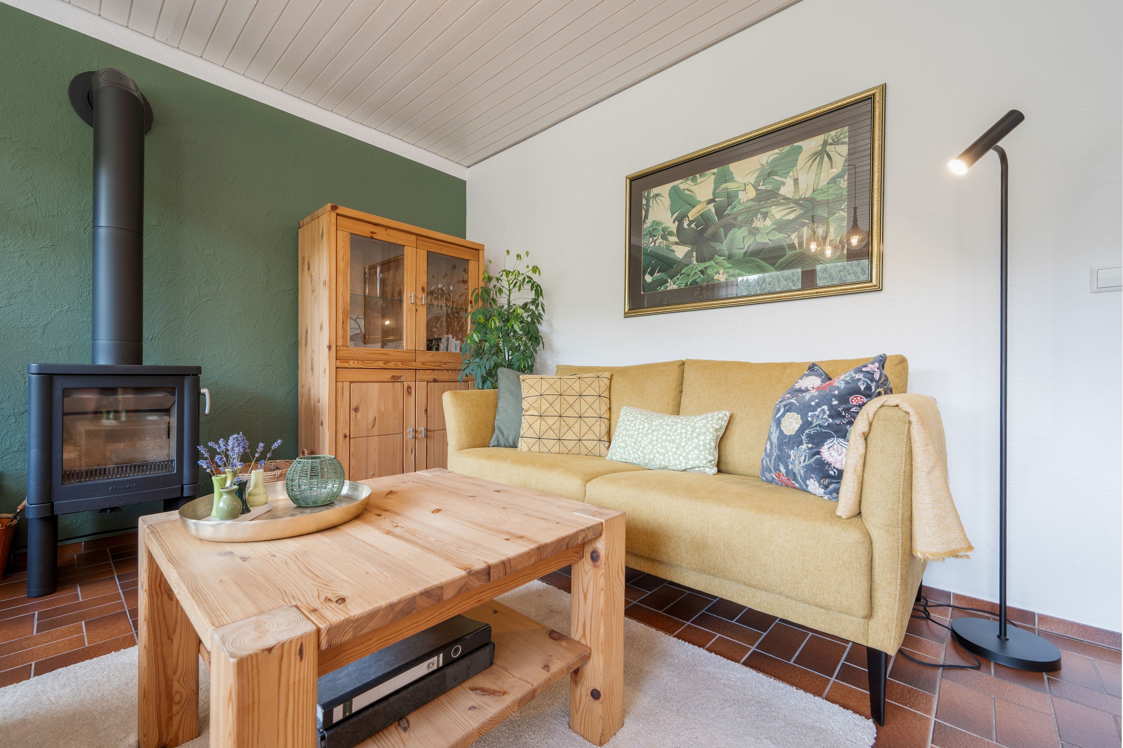 Ein gemütliches Wohnzimmer mit einer Couch, einem Holztisch, einem Schrank, einem Kamin und einem Bild an der Wand.