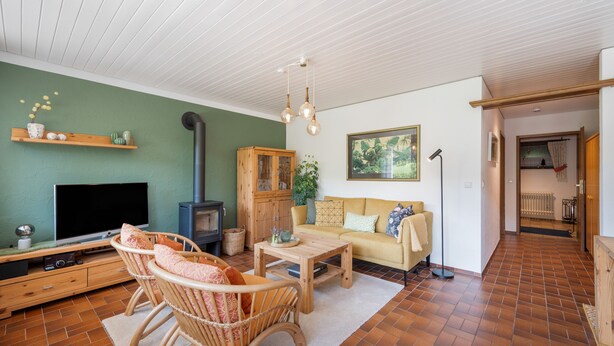 Ein Wohnzimmer mit Fernseher, einer Couch, Holzmöbeln und einem Kamin.