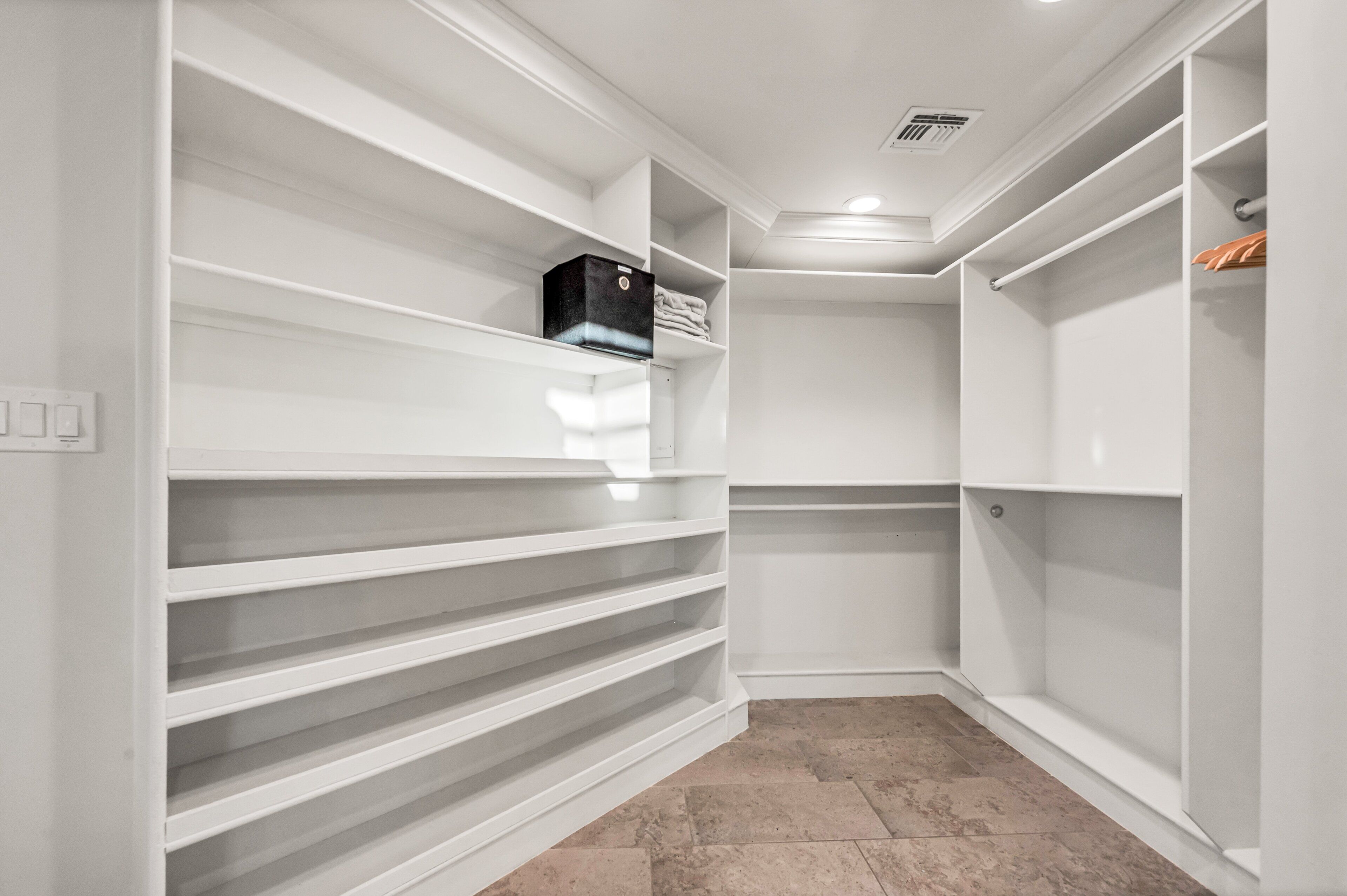 Un dressing avec des étagères blanches et un sol carrelé.