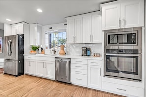 A modern kitchen with stainless steel appliances, white cabinetry, and a dishwasher.