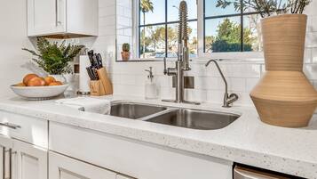 A modern kitchen with a double sink, a large vase, and a potted plant.