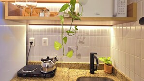A kitchen with a microwave, a kettle, a sink, and a potted plant. - Jardins do Atlântico By Hosppedar (João Pessoa)