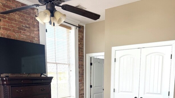 A bedroom with a bed, a dresser, a television, a ceiling fan, and a window with blinds. - The RoofTop Reserve (Vidalia)
