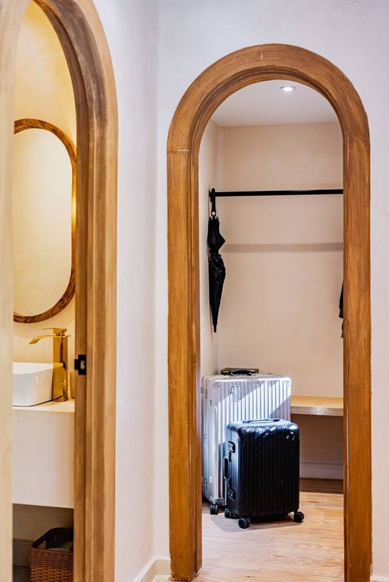 Een gang met houten bogen, een spiegel, een radiator en een zwarte tas aan een kapstok.