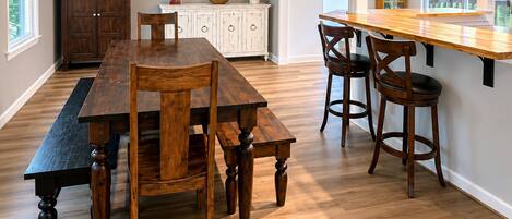 A dining area with a wooden table and chairs, a white cabinet, and a framed sign on the wall.