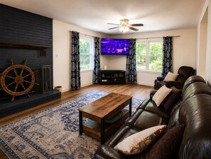 Ein Wohnzimmer mit einer Ledersofa, einem Holztisch, einem Fernseher und einem Kamin.