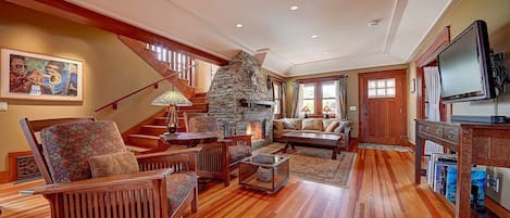 A spacious living room with a stone fireplace, wooden furniture, and a television.