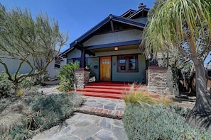 A two-story house with a stone foundation, a red front porch, and a blue exterior. - Historic Craftsman - Pet Friendly - Sleeps 6 (Long Beach)